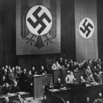 El canciller alemán Adolf Hitler (1889 - 1945) habla en el Reichstag de Berlín, Alemania, antes de la entrada de las tropas alemanas en Renania, el 7 de marzo de 1936. También aparecen en la foto Rudolf Hess y Joseph Goebbels. (Foto de Keystone/Hulton Archive/Getty Images